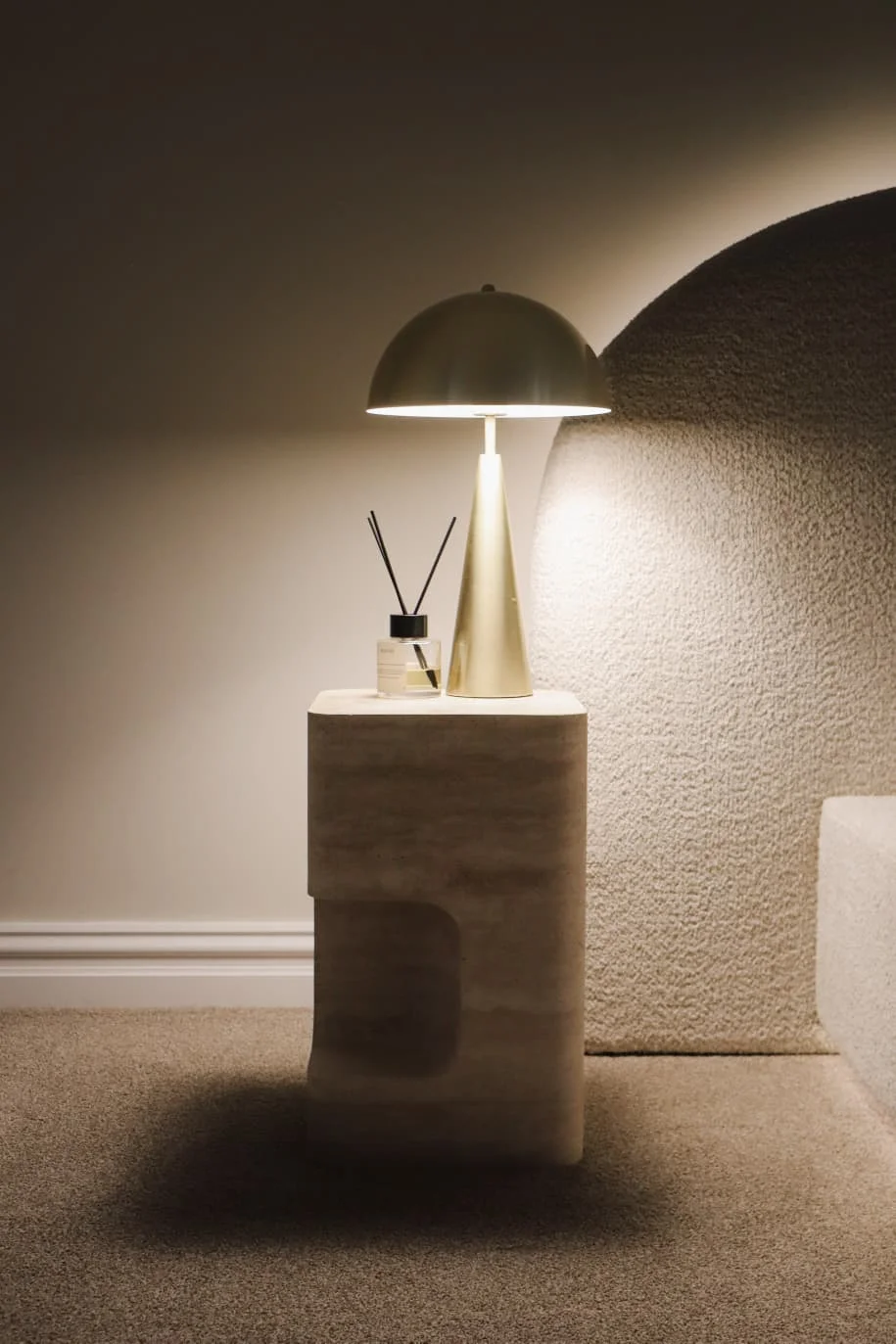 Sculptural stone bedside table with brass lamp
