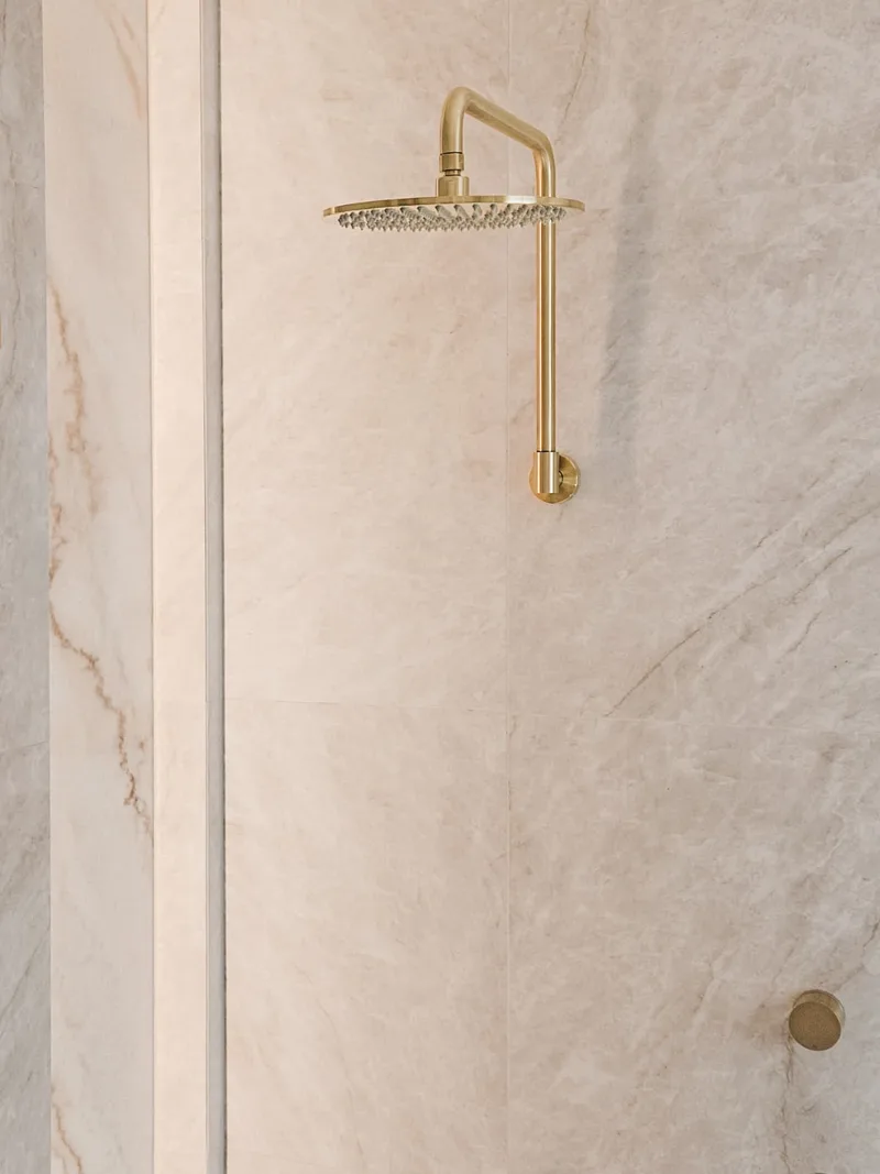 Full-height stone shower cladding with brass fixtures